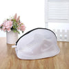 A white mesh laundry bag for shoes and delicates with a black zipper resting on a wooden surface.
