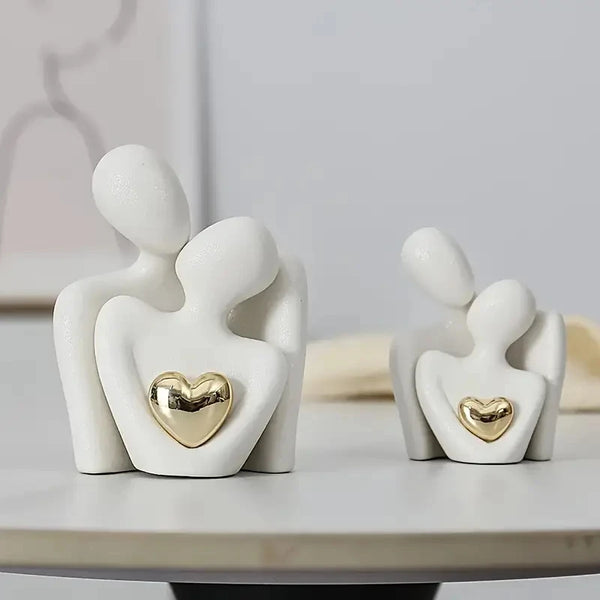 White ceramic statue depicting two embracing figures with gold heart accents for bedroom decor