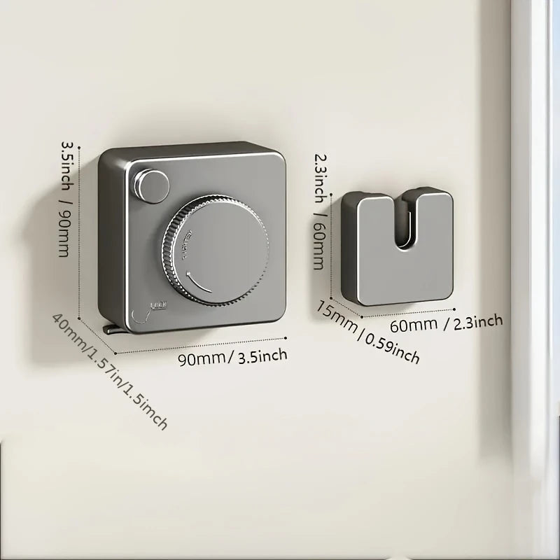 A gray retractable wire clothesline with a circular handle is mounted on a white wall.