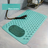Alfombrilla de masaje anti-resbalar color verde azulado con relieve y una herramienta de masaje verde, sobre un suelo gris cl