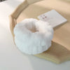A white microfiber wrist sweatband is displayed on a light wooden tray next to a small white card.