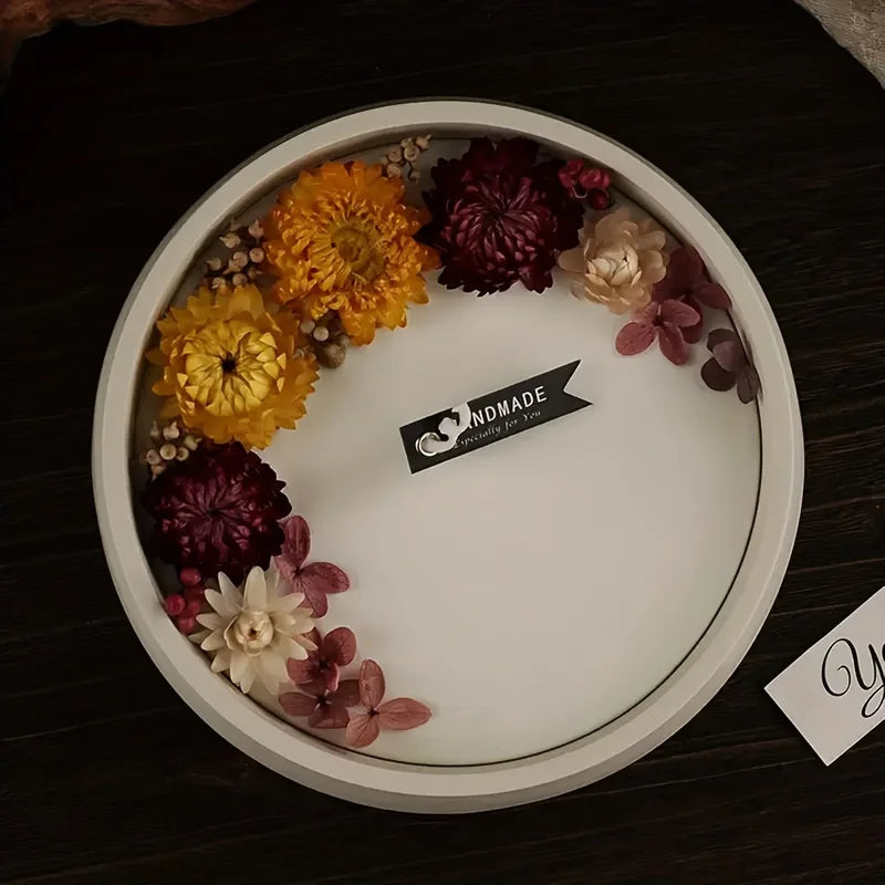 A white plate displays various dried flowers in shades of yellow, purple, and cream, with a black tag reading Handmade specia