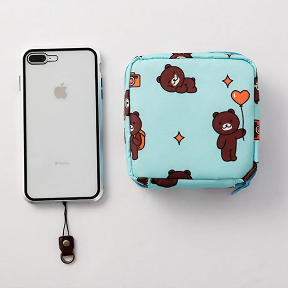 A light blue floral nylon sanitary pad storage pouch next to an iPhone.