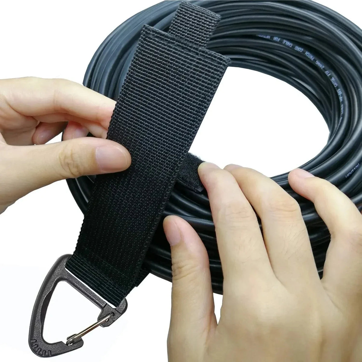 Hands are holding a black heavy-duty nylon cord organizer strap with a metal clip.