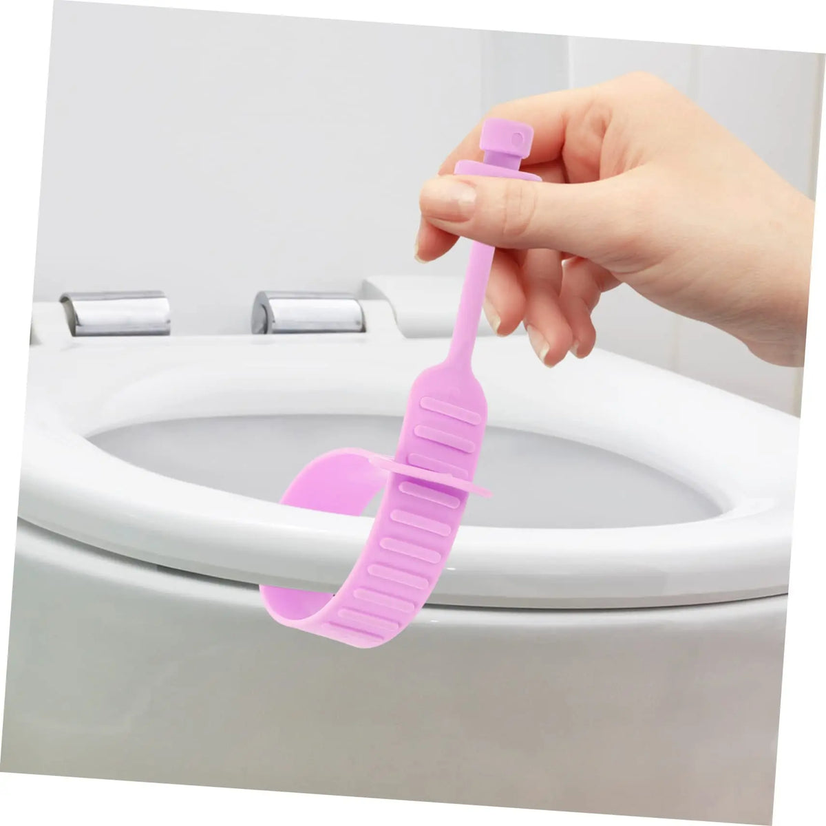A hand is lifting a pink silicone toilet lid lifter from the rim of a white toilet bowl.