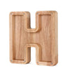 Lettre alphabet en bois H utilisée comme tirelire pour économiser.