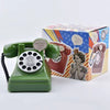 A vintage green rotary telephone and a box featuring a girl illustration are displayed on a white background.