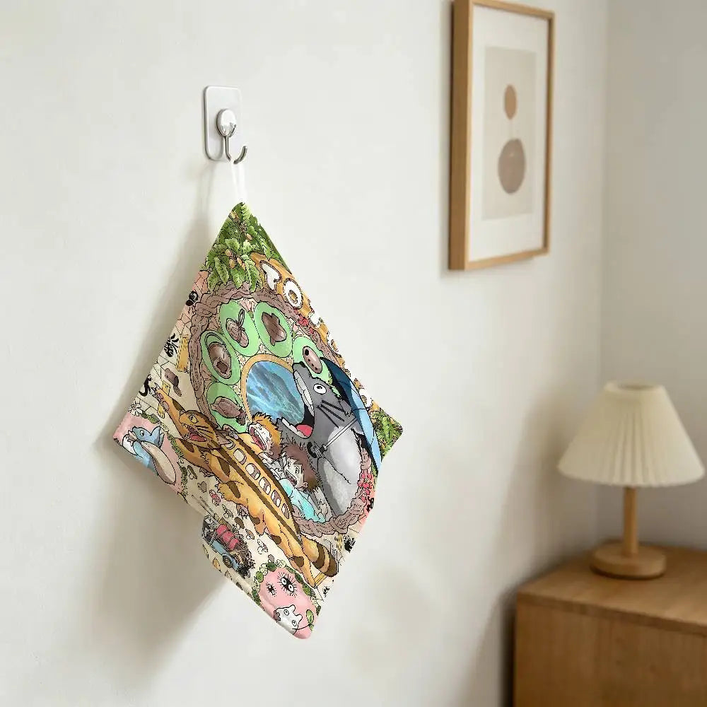 A hand wiping towel featuring a Totoro cartoon design hanging on a white wall.