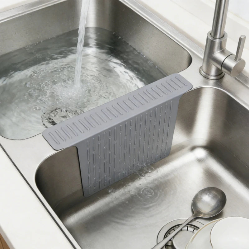 A non-slip silicone kitchen sink protector mat with drainage is placed inside a stainless steel kitchen sink.
