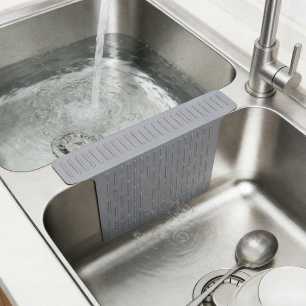 A non-slip silicone kitchen sink protector mat with drainage is placed inside a stainless steel kitchen sink.
