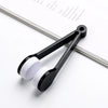 A black silicone cleaning tool with white pads for cleaning eyeglasses is shown on a white background.