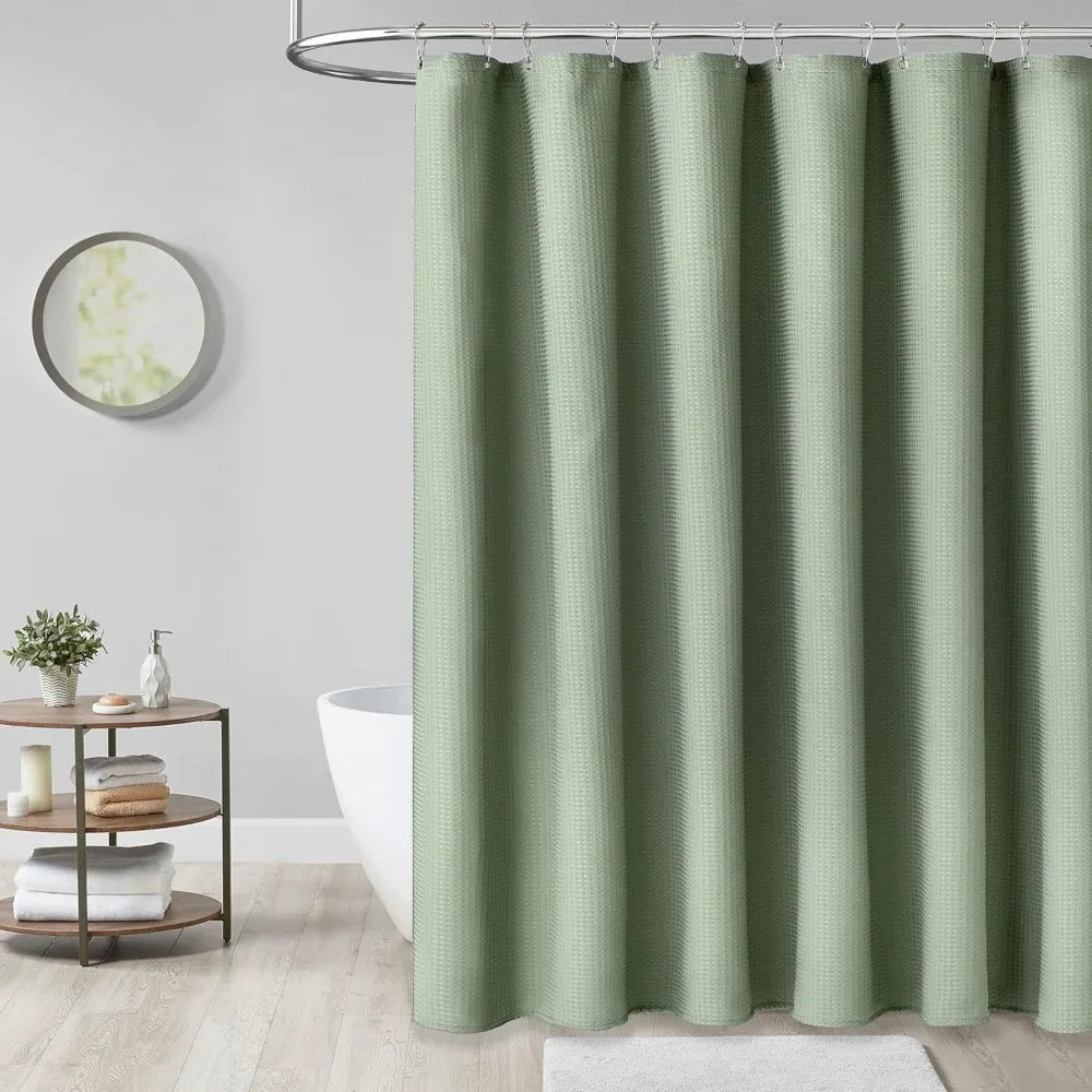 A floor-length, solid sage green waterproof shower curtain hanging on a metal rod.