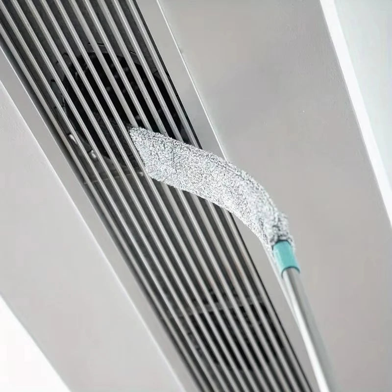 Nahaufnahme eines silbernen Mikrofasertrockners und Reinigungsbürsten-Sets, befestigt an einem Metallrohr oder Lüftungsgitter