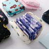 A collection of purple and white sanitary pads stored in a beige nylon pouch alongside various fabric pouches.