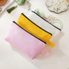 Three colorful zipper bags in pink, yellow, and white are displayed on a light surface.
