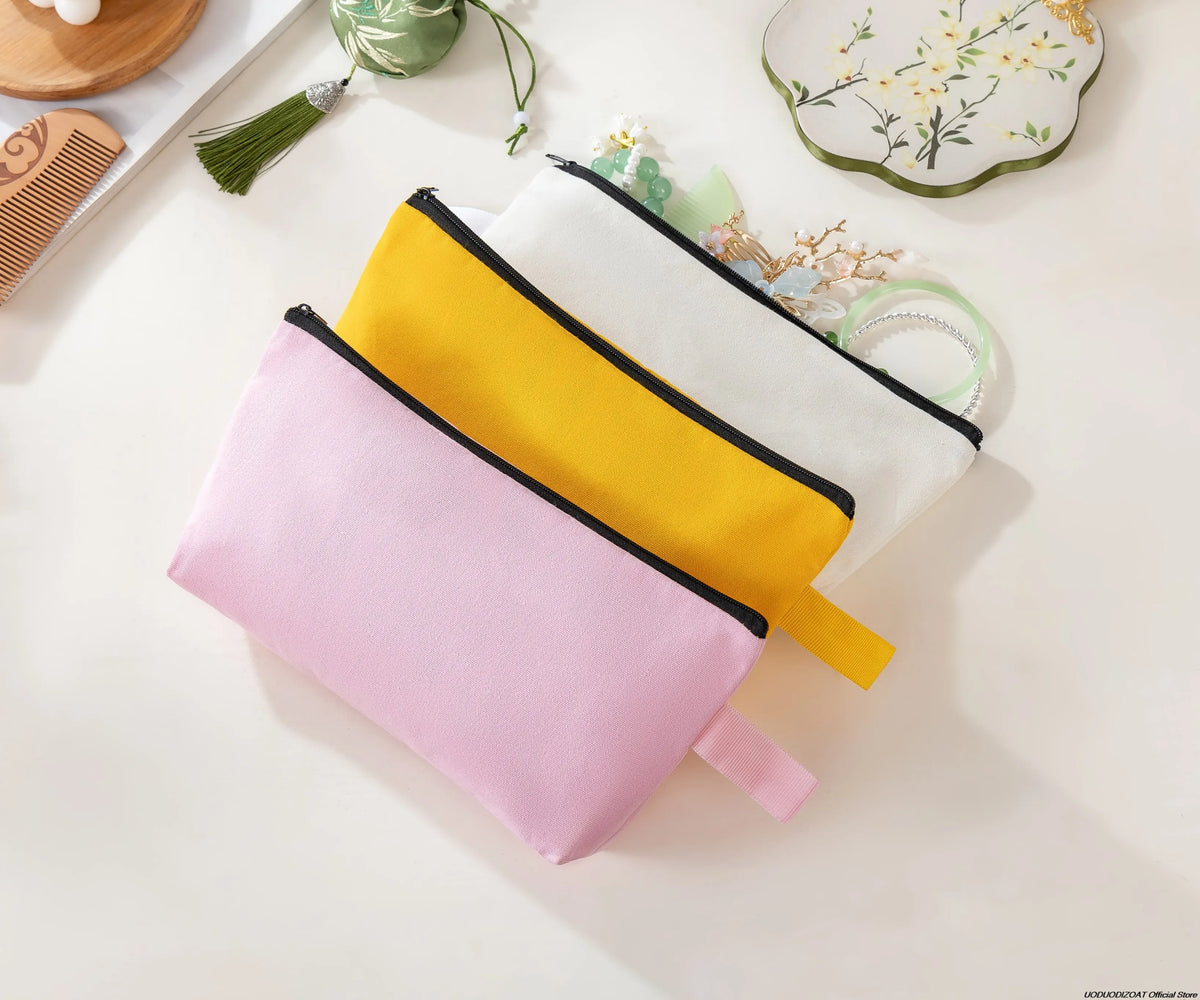 Three colorful zipper bags in pink, yellow, and white are displayed on a light surface.