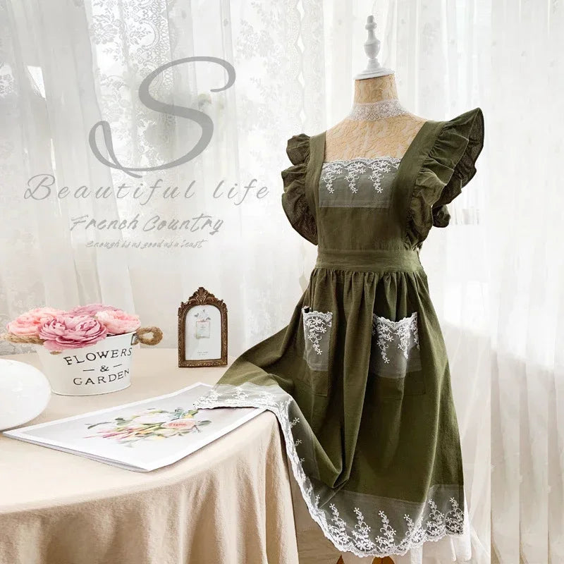 Salbei-grünes Leinen-Baumwoll-Schürzenkleid mit Spitzenverzierungen auf einem Mannequin.