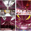 Close-up view of sheer pink chiffon draping fabric suspended from a ceiling for an event backdrop.