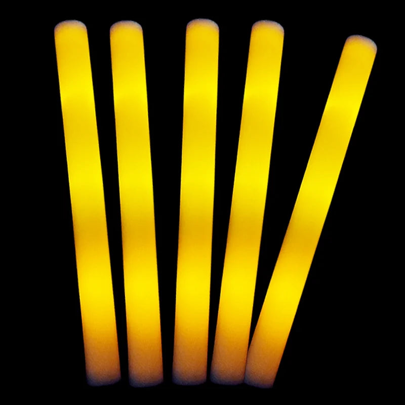 Eine Reihe leuchtend gelber LED-Glowsticks stehen vertikal vor einem schwarzen Hintergrund.