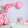 A display of pink and light blue balloons arranged in a curved shape against a white wall.