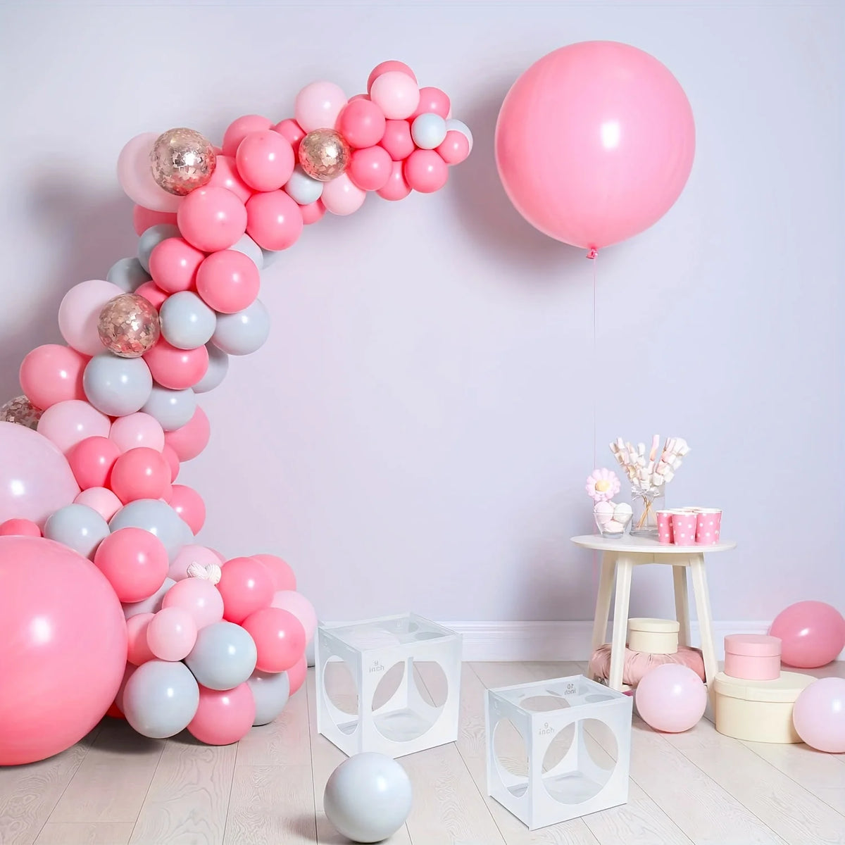 A display of pink and light blue balloons arranged in a curved shape against a white wall.