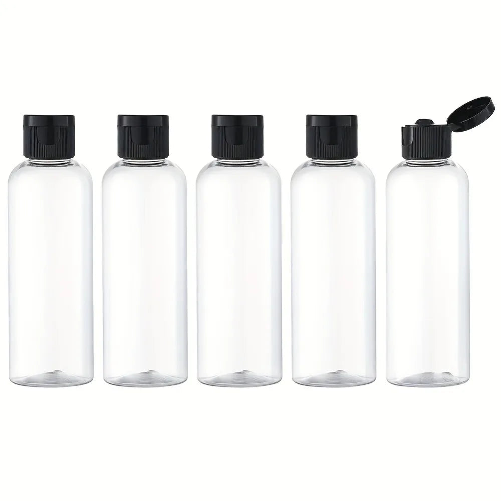 A set of four clear glass refillable travel bottles with black caps and a hinged cap.