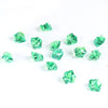 A collection of faceted, emerald green crystal crushed ice stones scattered on a white background.