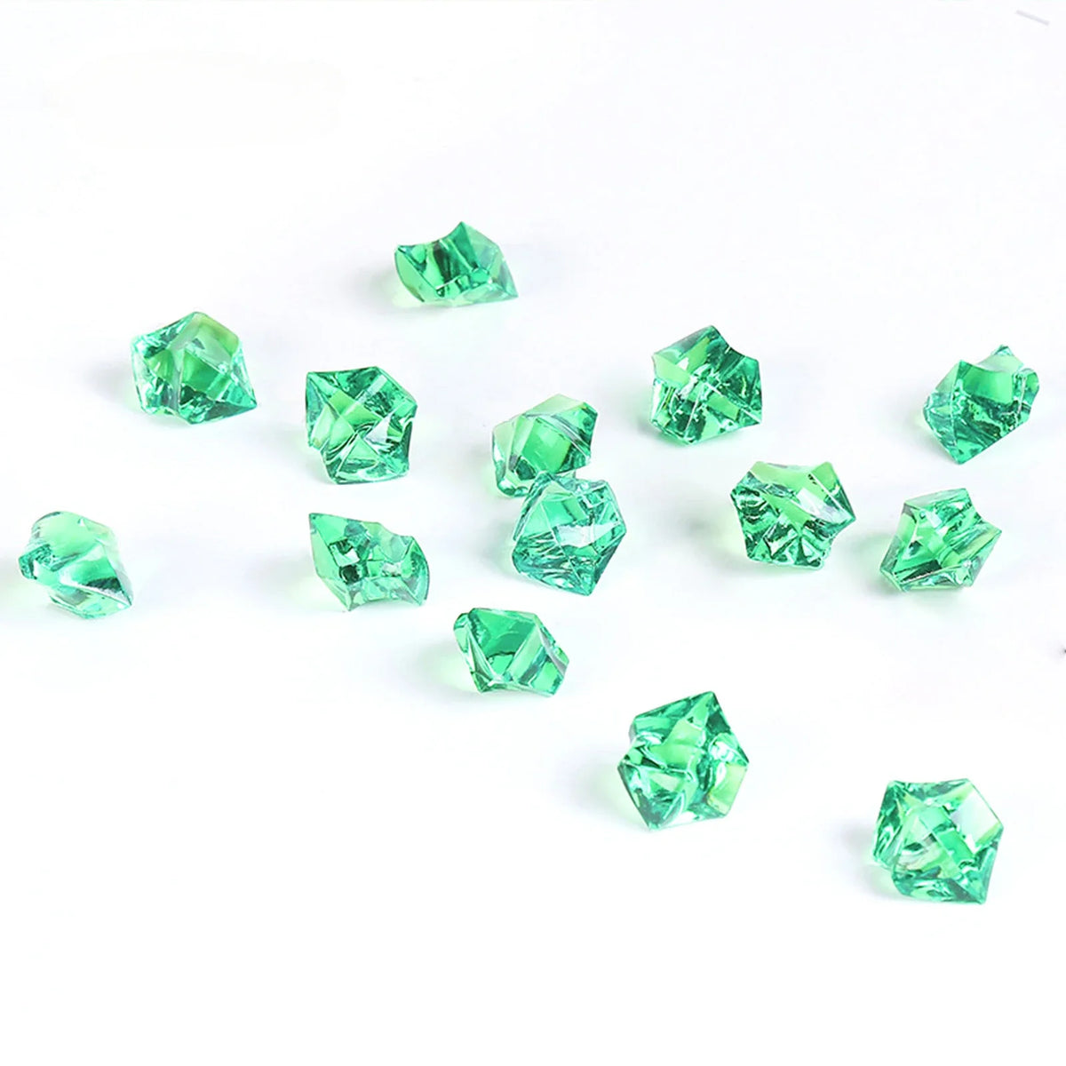 A collection of faceted, emerald green crystal crushed ice stones scattered on a white background.
