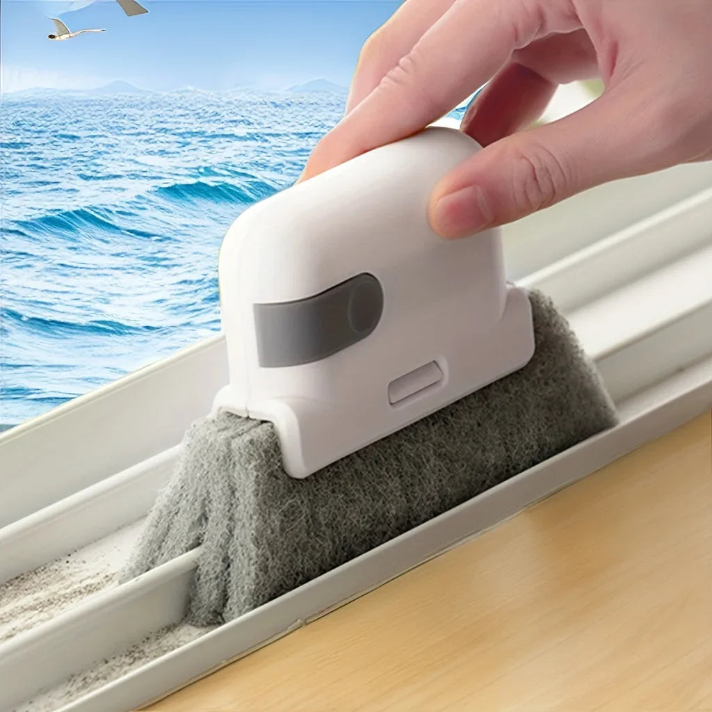 Una mano usa un cepillo de limpieza blanco para limpiar el vidrio de un marco de ventana.