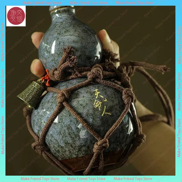 A hand holds a set of dark gray ceramic gourds tied with brown twine, featuring gold Chinese characters on the second gourd.