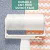 A roll of white cleaning cloths is displayed against a textured background with a green and coral pattern.
