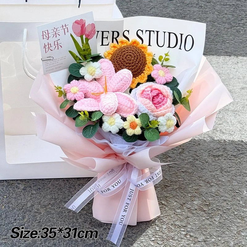 A bouquet of handmade crochet flowers featuring pink, yellow, and white blooms tied with a sheer ribbon.