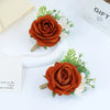 Boutonnière en soie orange vintage avec une rose orange profonde et des accents blancs sur fond clair.