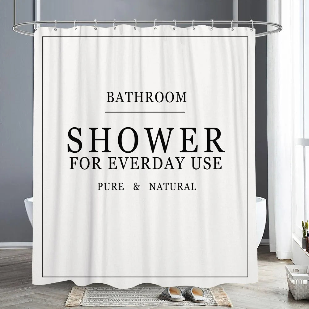 White shower curtain with black text reading Bathroom Shower for Everyday Use Pure & Natural hanging on a rod