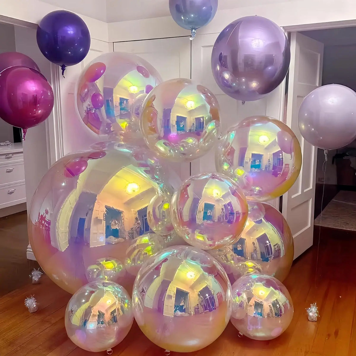 Eine Ansammlung irisierender holografischer Partyballons in lila und rosa Tönen, die in einem Raum hängen.