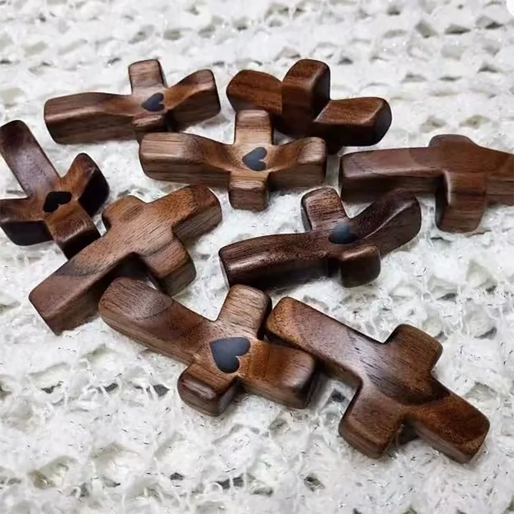 A collection of handcrafted wooden pocket crosses in various shades of brown resting on a white textured surface.