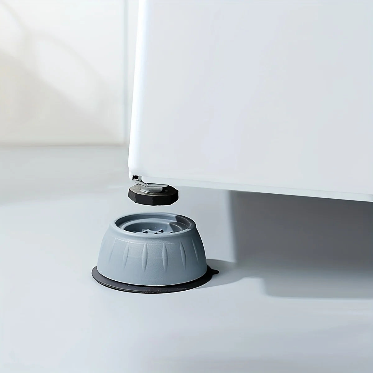 Anti-vibration feet for an appliance, showing a white panel resting on a gray rubber base.