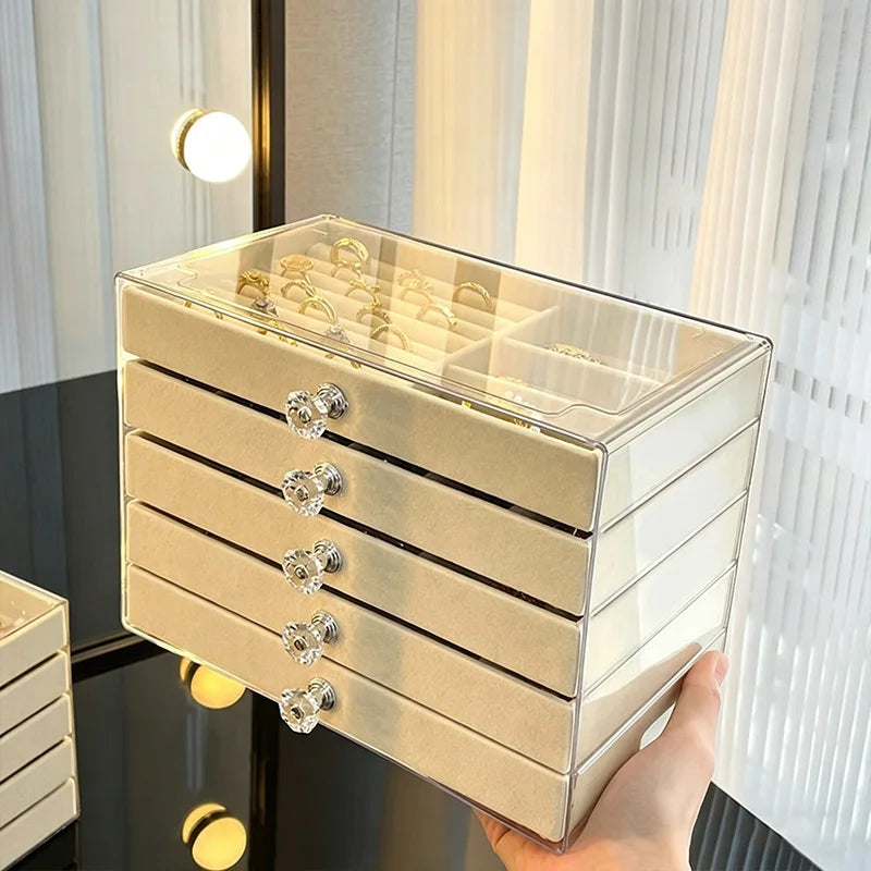 A clear acrylic 5-tier desktop jewelry organizer rack with gold accents is being held against a light background.