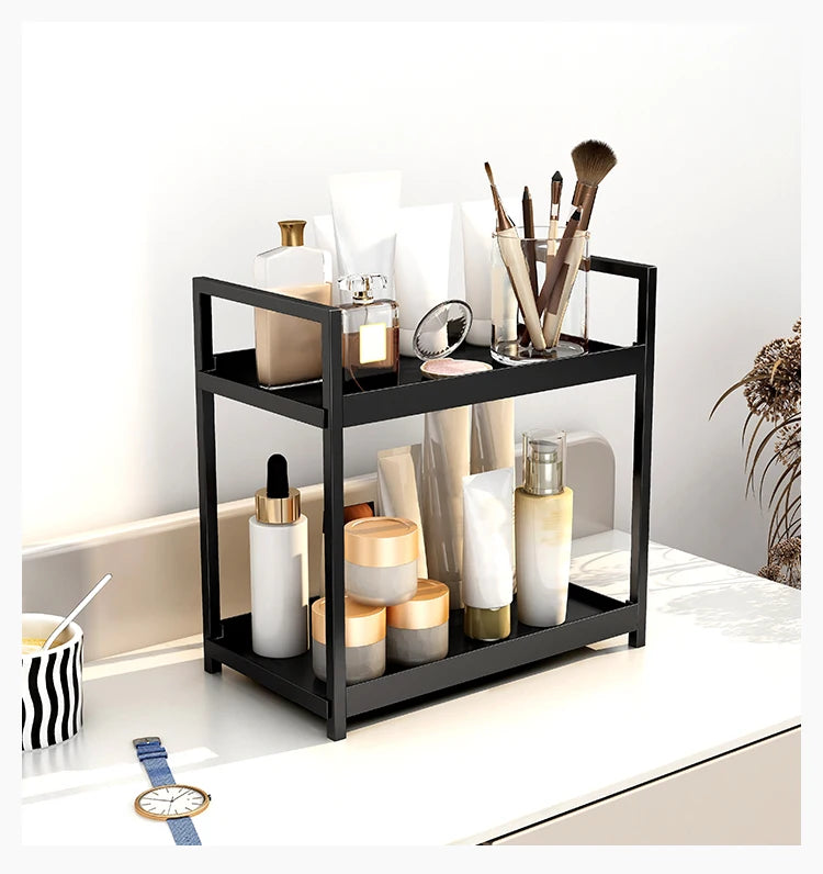 A black two-tier desktop storage rack holds various glass and ceramic beauty products like bottles and brushes.
