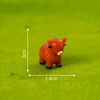 An orange resin figurine of a Highland cow placed on green felt with measurement lines.