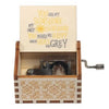 A mini wooden music box with a hand crank and a lid featuring text about sunshine and grey.