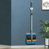 A blue ergonomic long handle broom and dustpan set leaning against a gray wall.