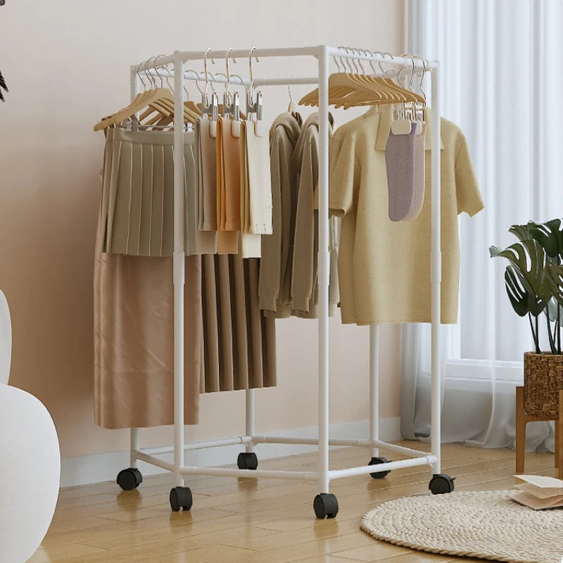 A white rotating hexagon clothes rack with wooden hangers displaying various garments in a bright indoor setting.