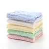 Una pila de cinco toallitas húmedas orgánicas de algodón para bebé y cara de colores pastel en azul claro, blanco, amarillo, 