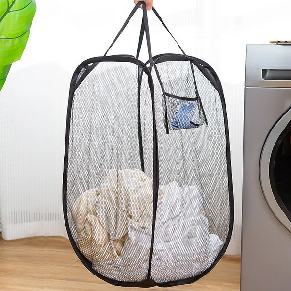 A black mesh laundry basket with side pockets filled with white clothes hanging from a hanger.