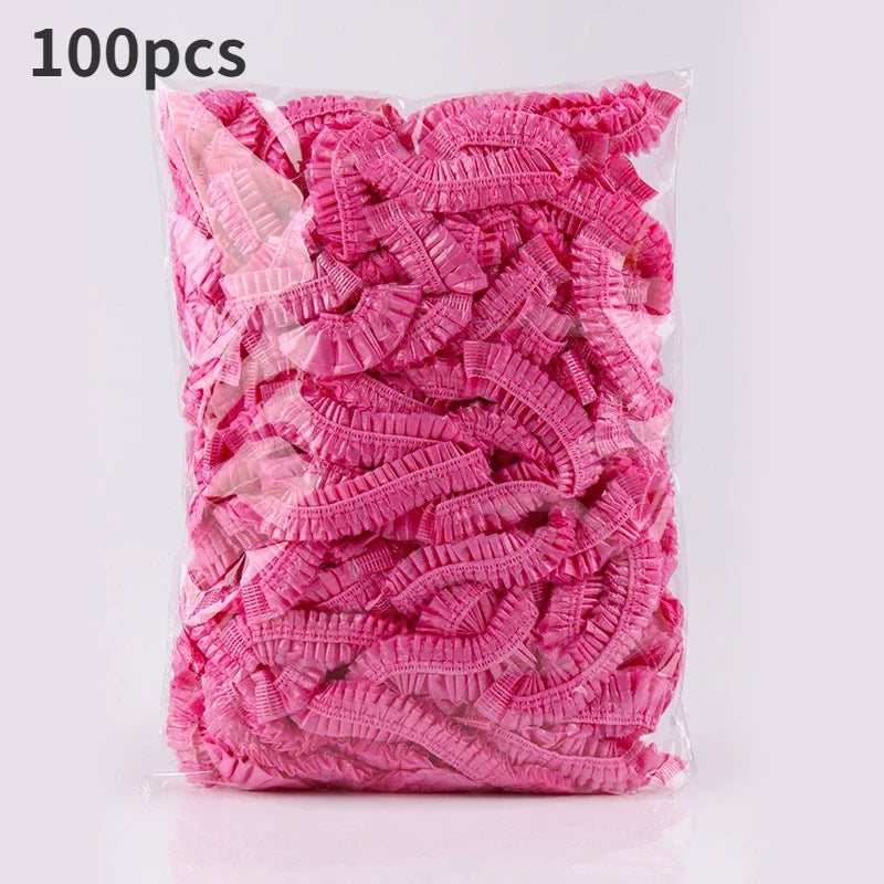 A package of 100 pink reusable transparent shower caps.