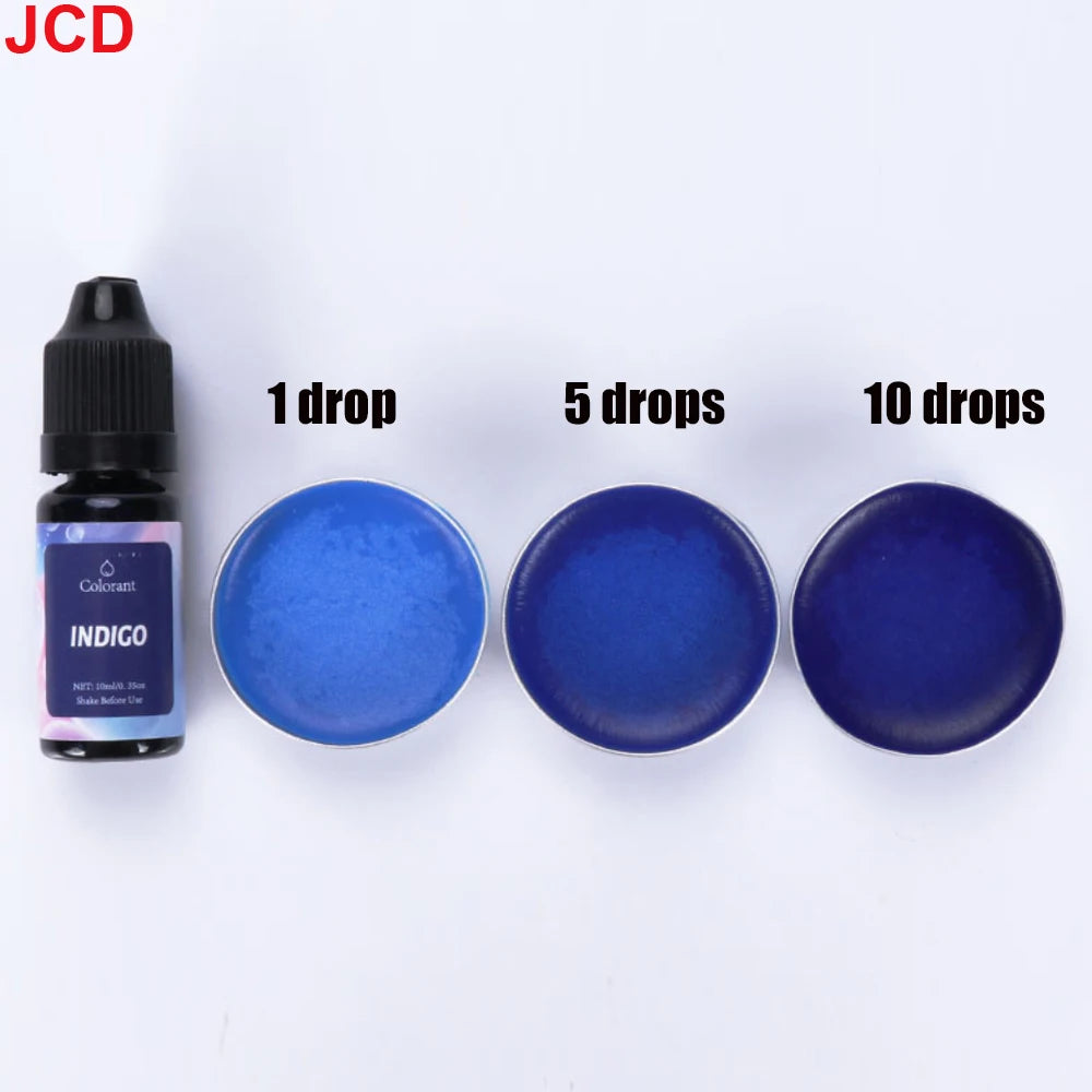 A bottle of Indigo liquid candle dye next to three petri dishes showing single, five, and ten drops of the blue color.