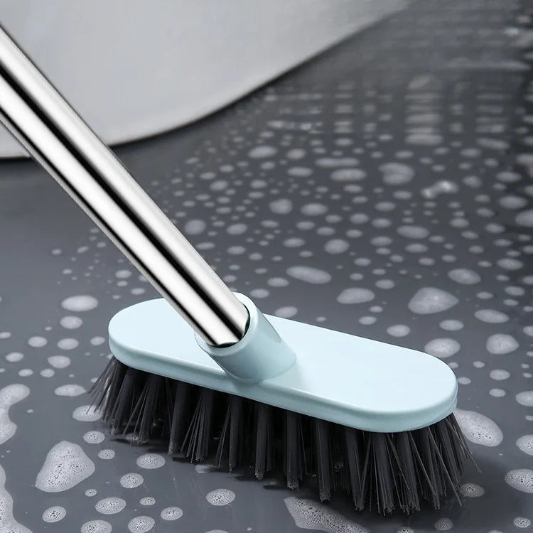 A light blue heavy-duty floor scrub brush with a long metal handle is shown against a dark surface.