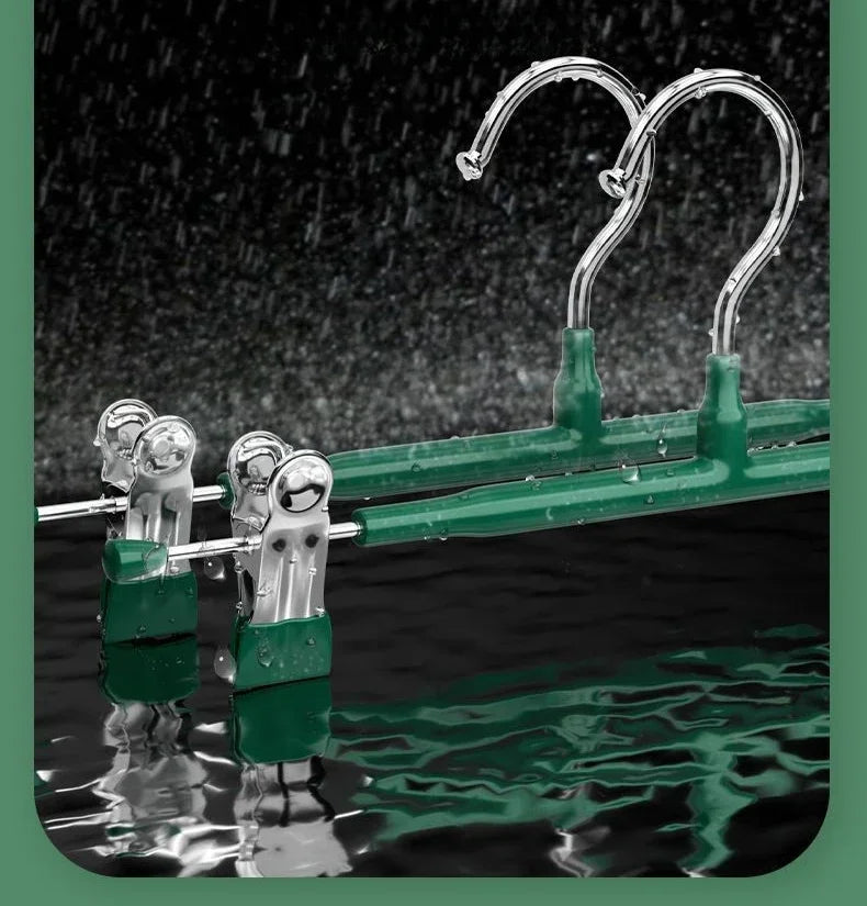 A set of stainless steel adjustable clothing hangers with green plastic components and chrome hooks.