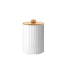 A white cylindrical bathroom countertop organizer with vertical ridges and a wooden lid.